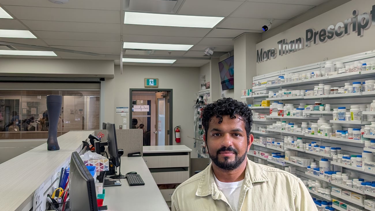 Tarun Fernandez, a young pharmacist standing behind the counter
