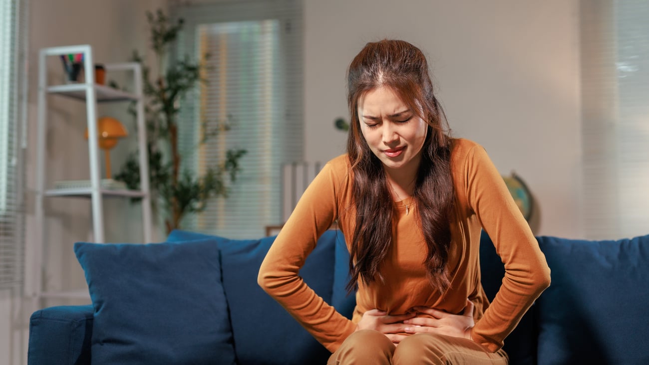 Young woman sitting on a couch in severe pain