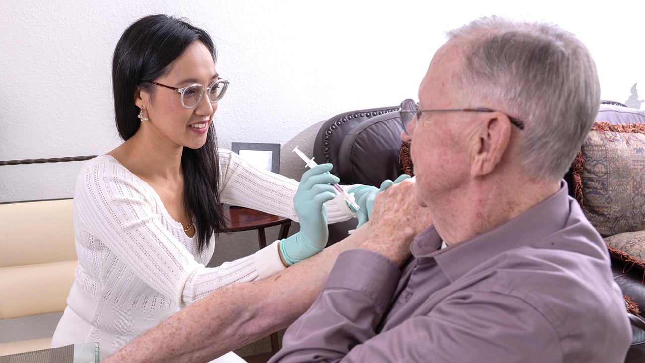 Pharmacist Yolanda Yeung giving a vaccine to a patient in his home