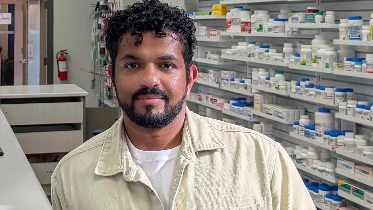 Tarun Fernandez, a young pharmacist standing behind the counter