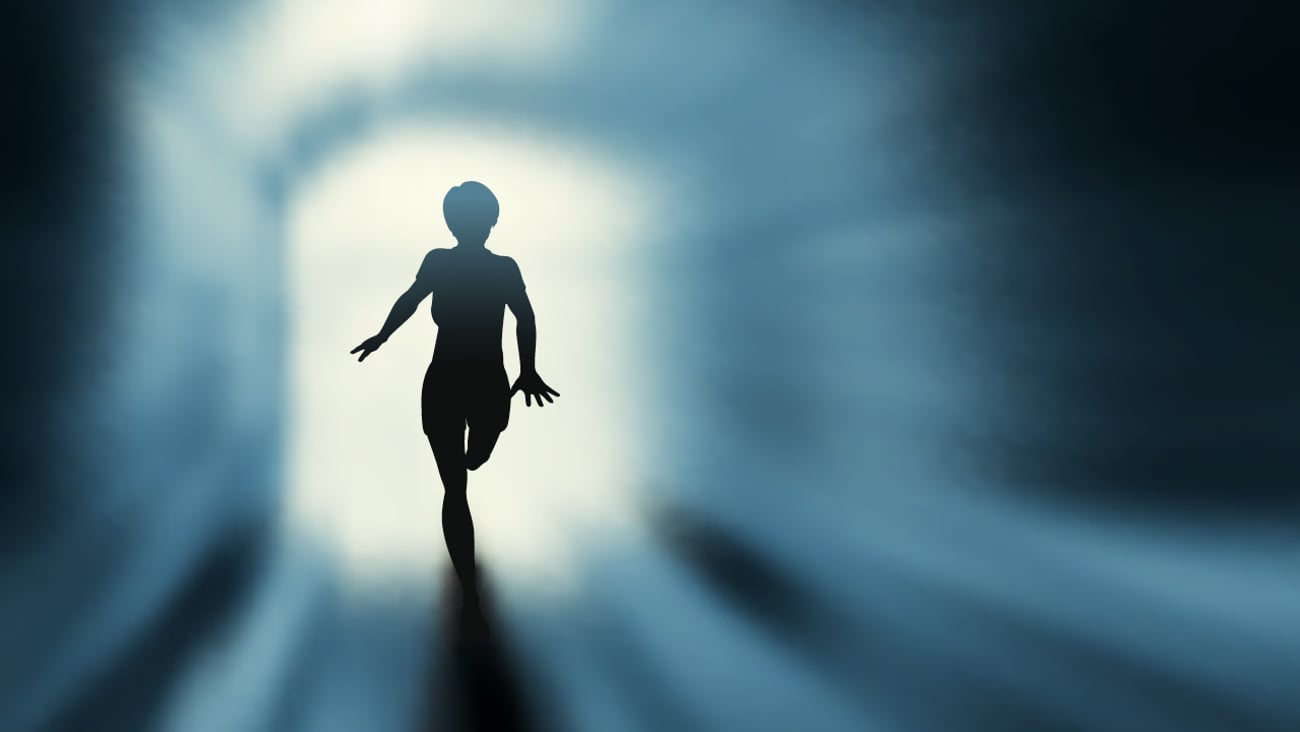 A shadowy figure running towards the light coming through an open door