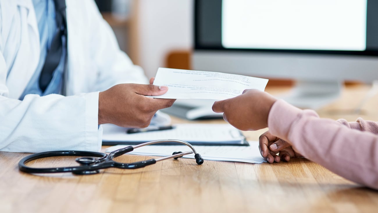 A doctor hands a patient a sick note.