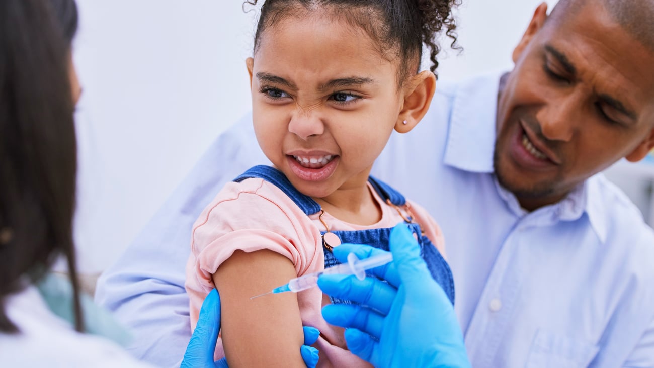 Cute little girl scrunching her face in anxiety about to get a vaccine