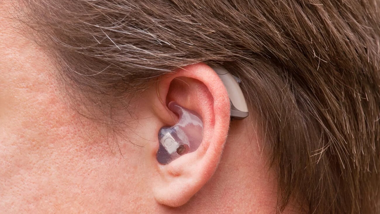 Close-up of a man ear with a high-tech digital behind-the-ear-hearing device; Shutterstock ID 104835074