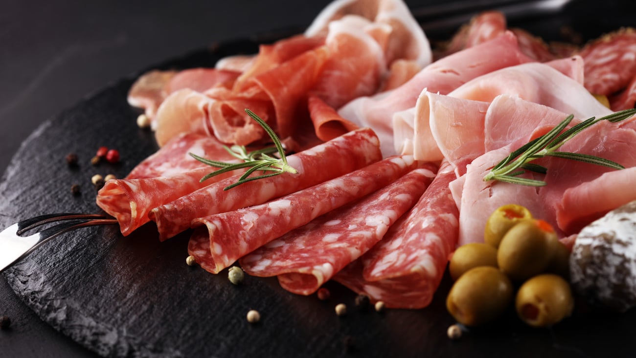 Marble cutting board with prosciutto, bacon, salami and sausages on wooden background. Meat platter; Shutterstock ID 1224835114