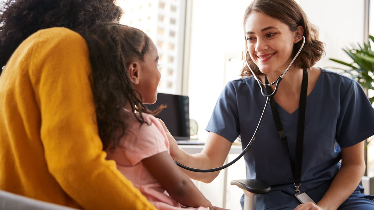 Female Pediatrician Wearing Scrubs Listening To Girls Chest With Stethoscope In Hospital Office; Shutterstock ID 1323802859
