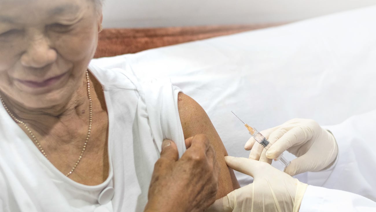 Senior vaccination concept. Elderly getting immune vaccine at arm for flu shot, pneumonia, and shingles(MMR) in hospital by nurse. Doctor giving an injection to older people patient in clinic.; Shutterstock ID 1363033895