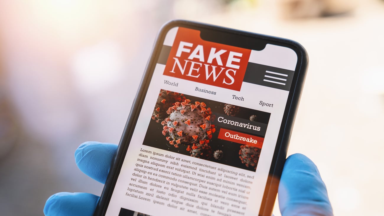 Online Corona Fake news on a mobile phone. Close up, man reading Fake news or articles about covid-19 in a smartphone screen application. Hand with gloves holding smart device. COVID19 nCov Outbreak.; Shutterstock ID 1716020299