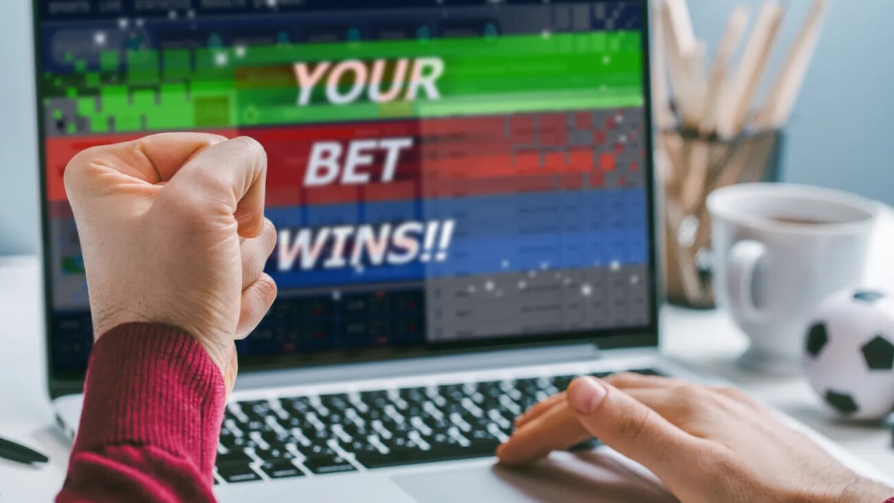 Cropped shot close up of male fist clenched with triumph in front of laptop screen. Man celebrating money win at bookmaker's website, his bet played.; Shutterstock ID 1750604135