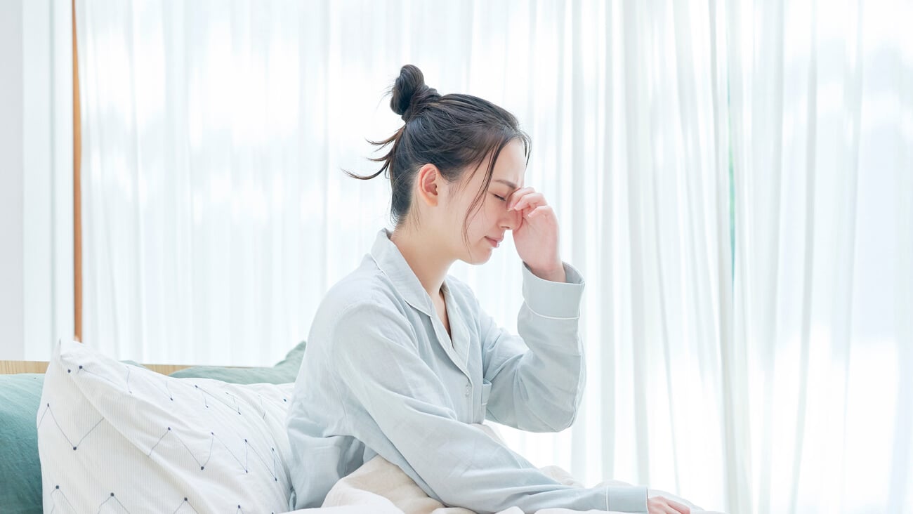 Asian woman waking up with headaches; Shutterstock ID 1815169883