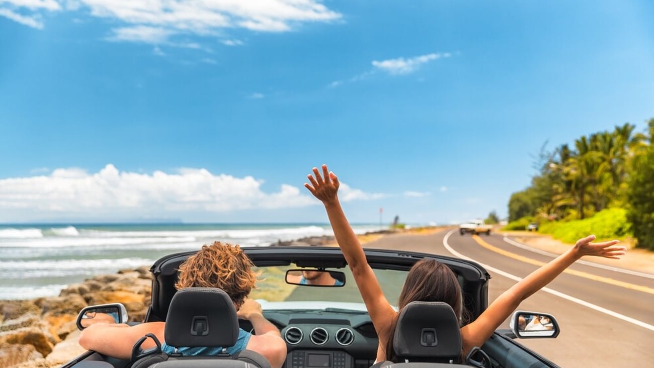 Road trip car holiday happy couple driving convertible car on summer travel Hawaii vacation. Woman with arms up having fun, young man driver; Shutterstock ID 2115317861