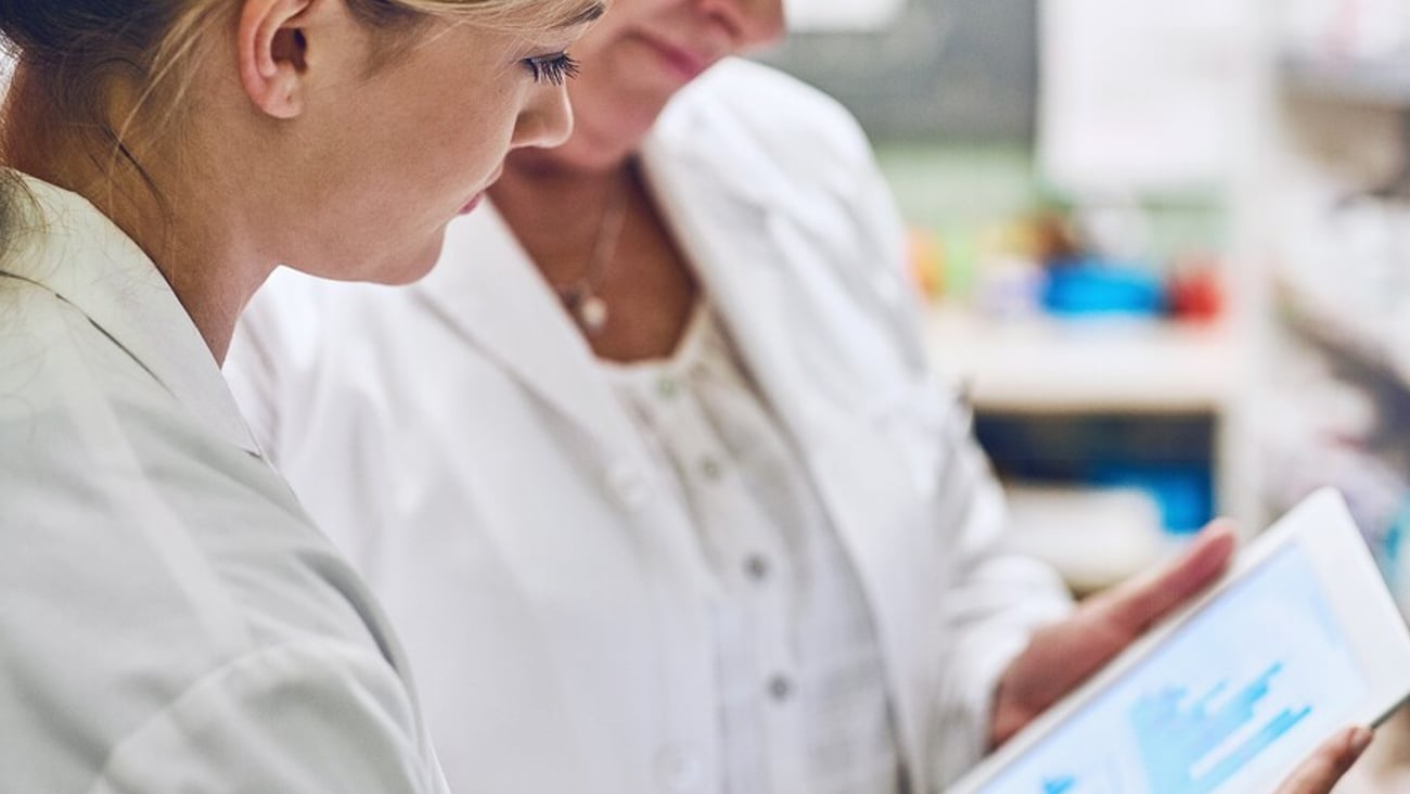 Pharmacist, women and together on tablet for charts, stock or sales stats with reading for analytics. People, mentor and intern on digital touchscreen, application or inspection with graphs at store; Shutterstock ID 2463695177