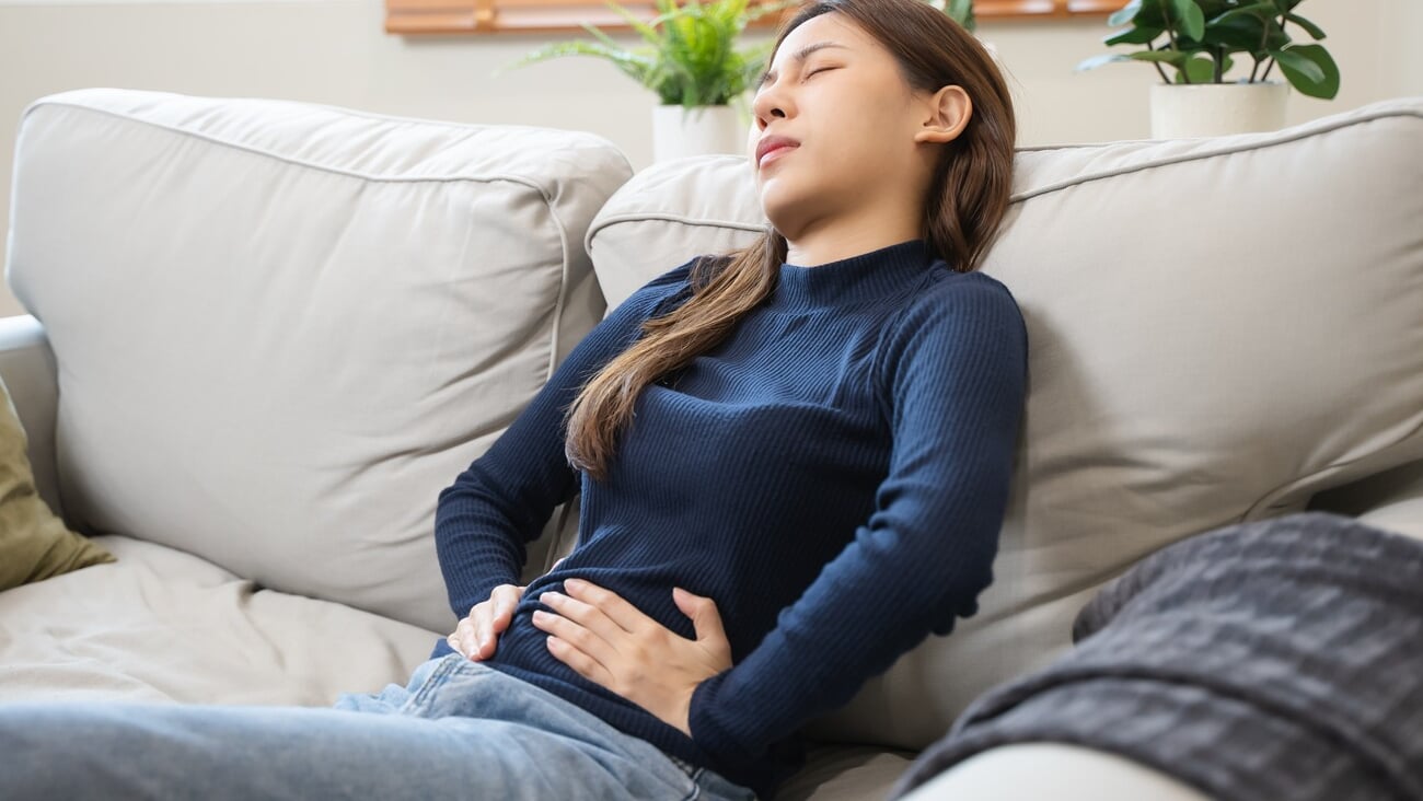 young woman gripping her stomach have abdominal pain .; Shutterstock ID 2467235017
