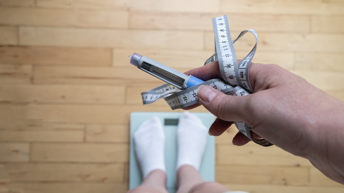 Ozempic Insulin injection pen for diabetics and weight loss. Woman weighs herself and holds Ozempic in her hand. Weight loss concept.; Shutterstock ID 2470013631