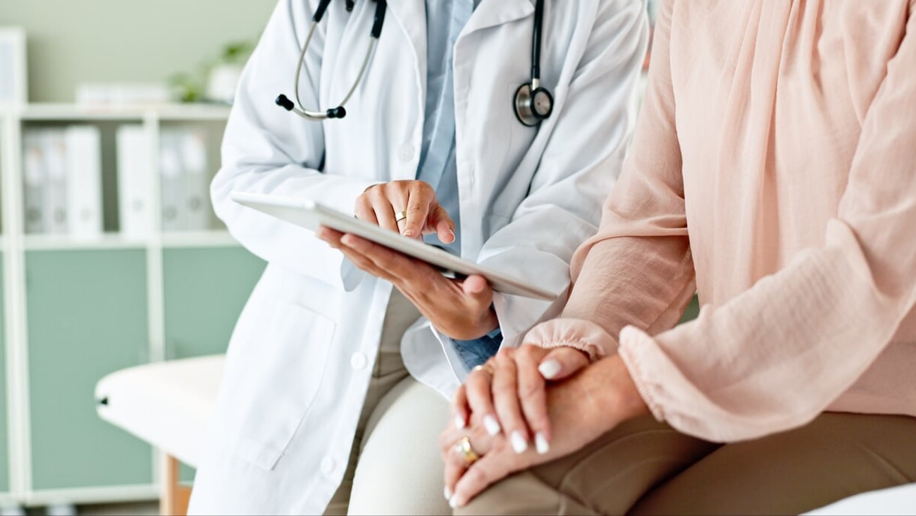 Clinic, tablet and hands of doctor with patient for consulting, medical service and help in hospital. Healthcare, telehealth and people on digital tech for diagnosis, online results and insurance; Shutterstock ID 2472677039