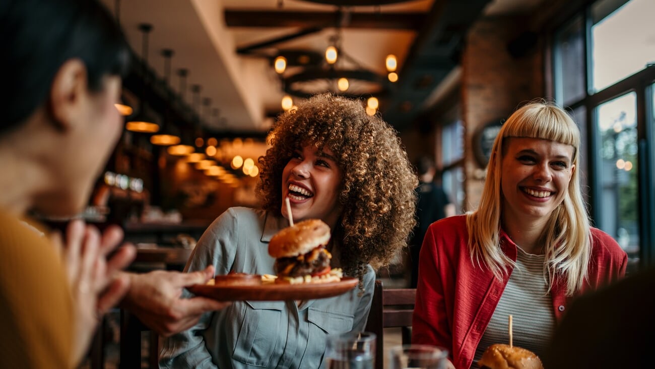 Waiter serving food to a group of customers at a restaurant; Shutterstock ID 2480557461
