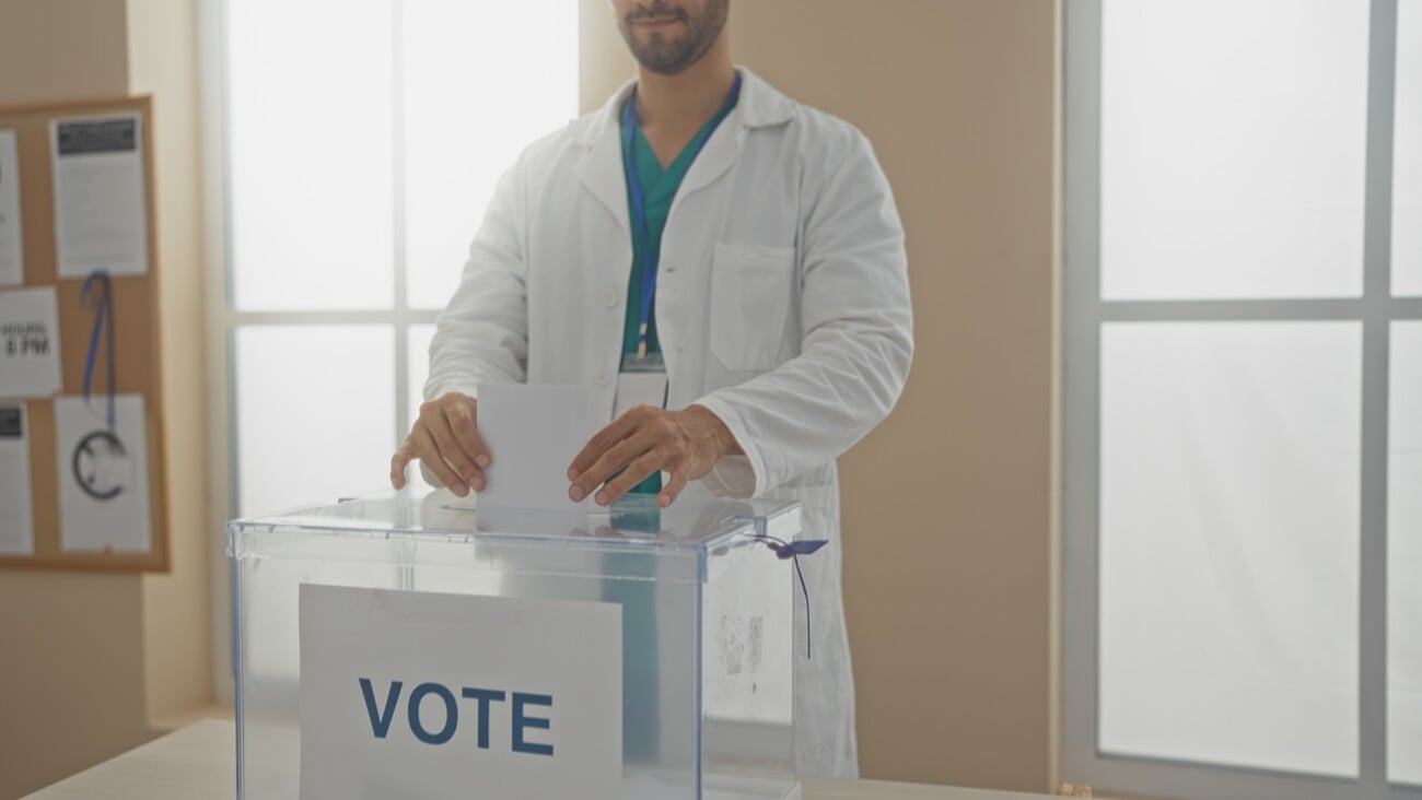 Young hispanic man voting indoors in an electoral college room, casting a ballot.; Shutterstock ID 2520044805