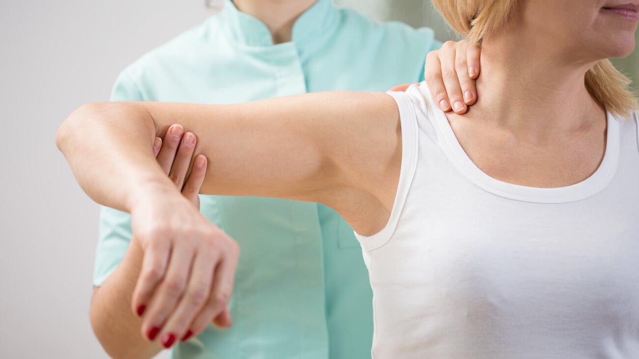 Physical therapist diagnosing patient with painful arm; Shutterstock ID 260864429