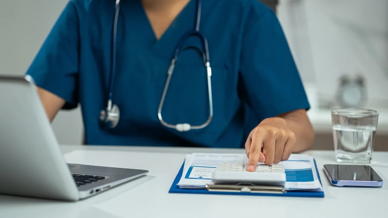 Doctor physician with stethoscope calculate medical fee costs or revenue. practitioner use calculator at clinic.; Shutterstock ID 2636957771