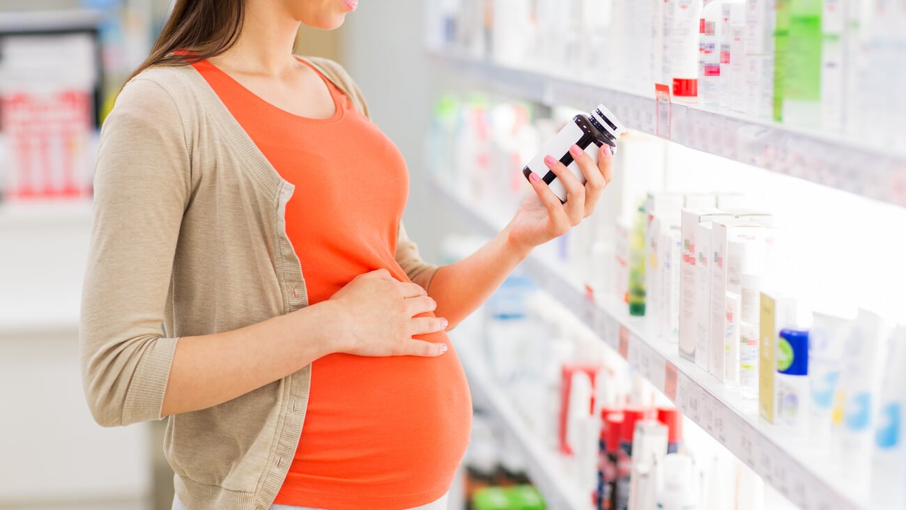 pregnancy, medicine, pharmaceutics, health care and people concept - close up of pregnant woman reading label on medication jar at pharmacy; Shutterstock ID 326633096