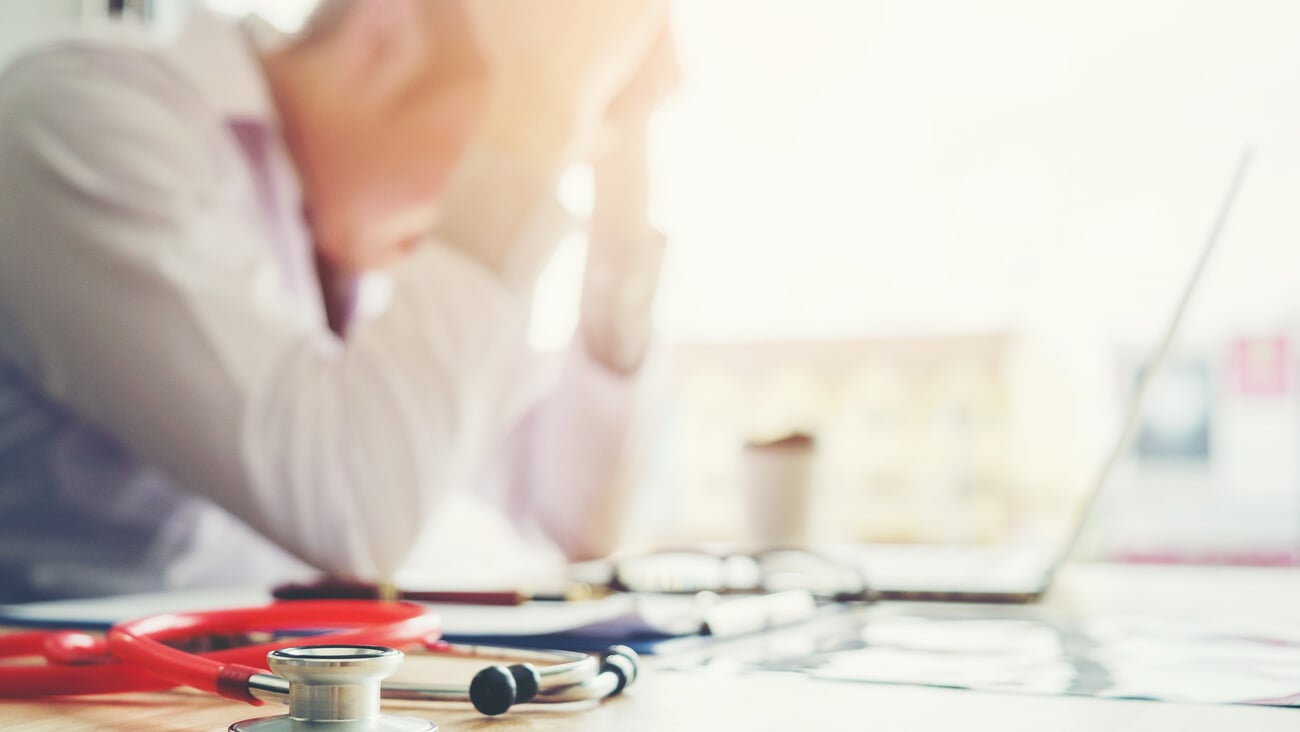 Stethoscope and doctor sitting with laptop stress headache about work in hospital; Shutterstock ID 754376389