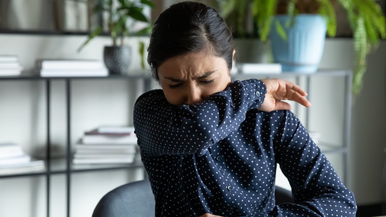 woman sneezing into her elbow