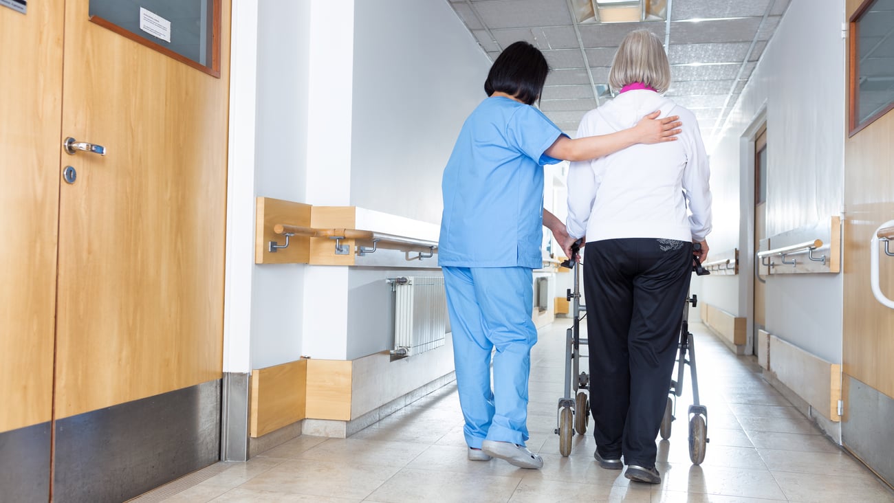 Nurse guiding an older woman down the hallway