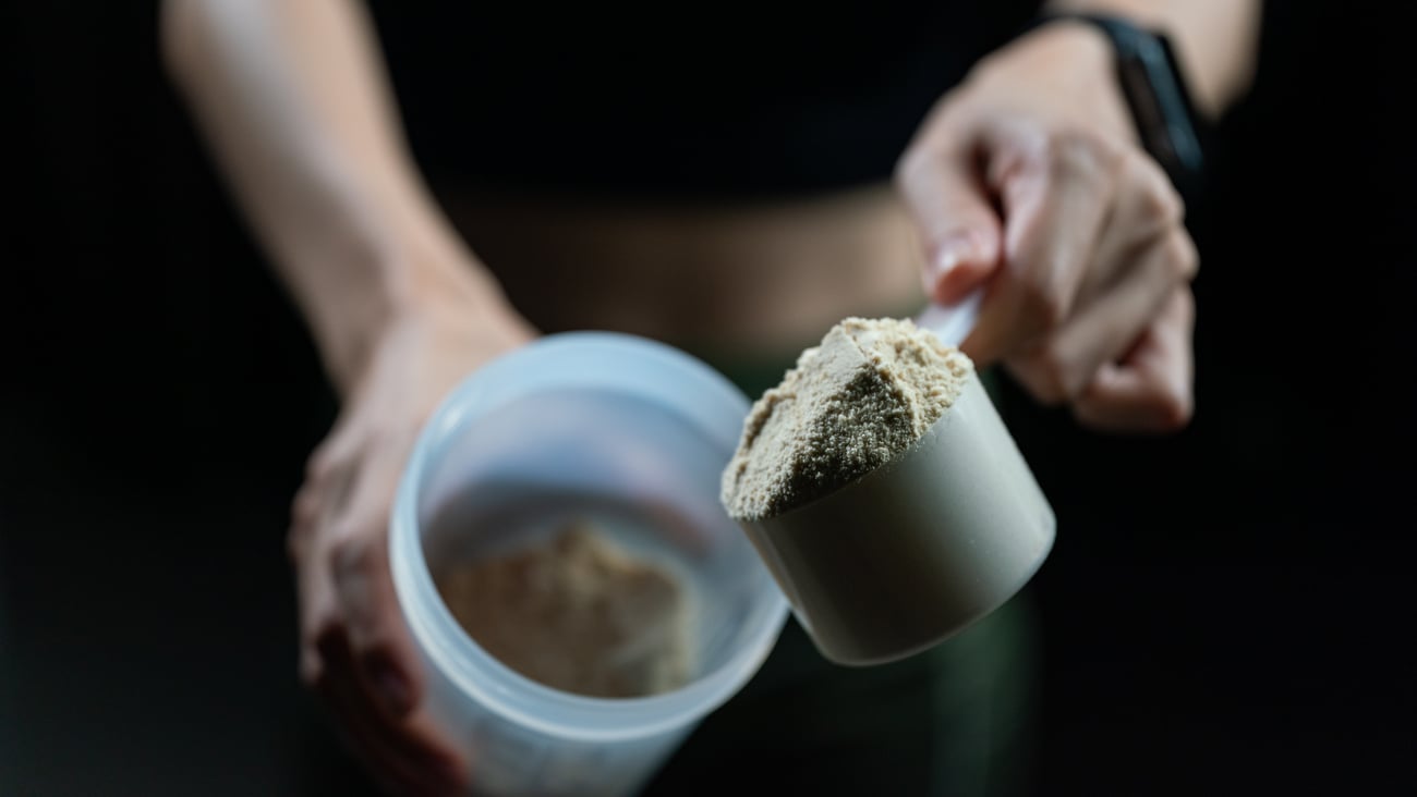 Two hands scooping out a heaping portion of protein powder