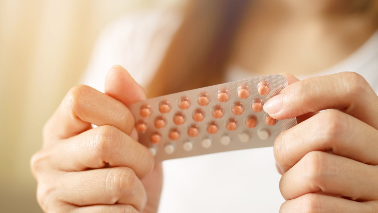 Close up of young woman's hands holding a sleeve of birth control pills