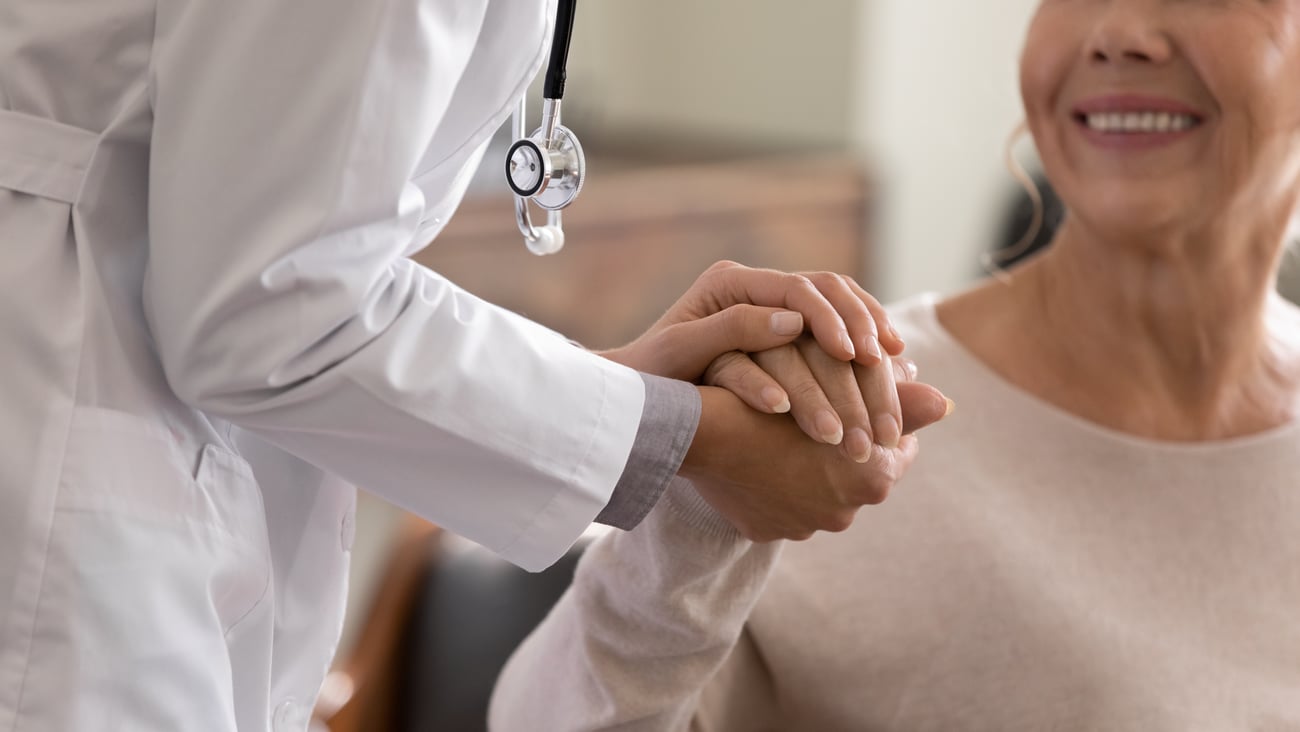 Close up of doctor holding smiling female patient's hand