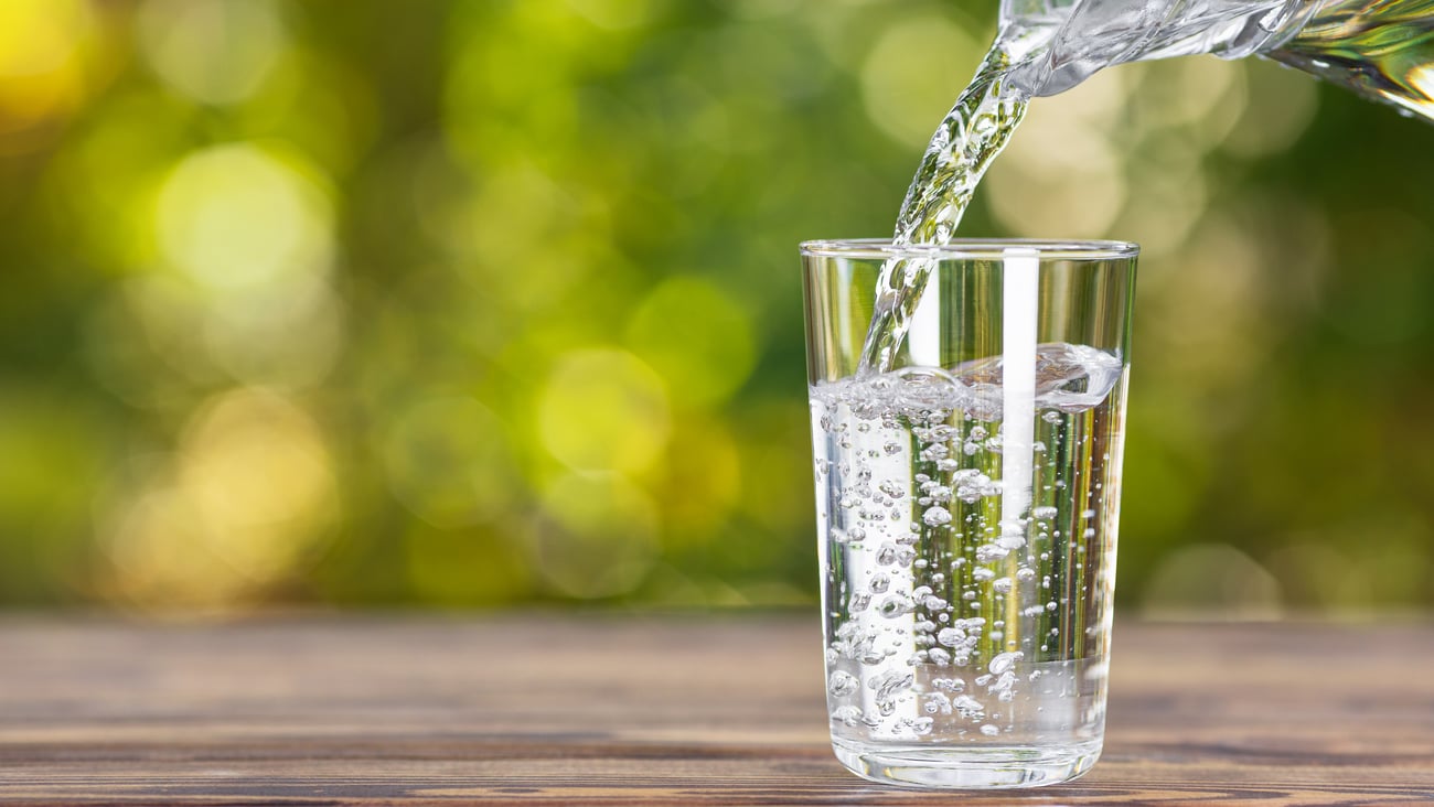 Clear water pouring from a glass jug into a glass