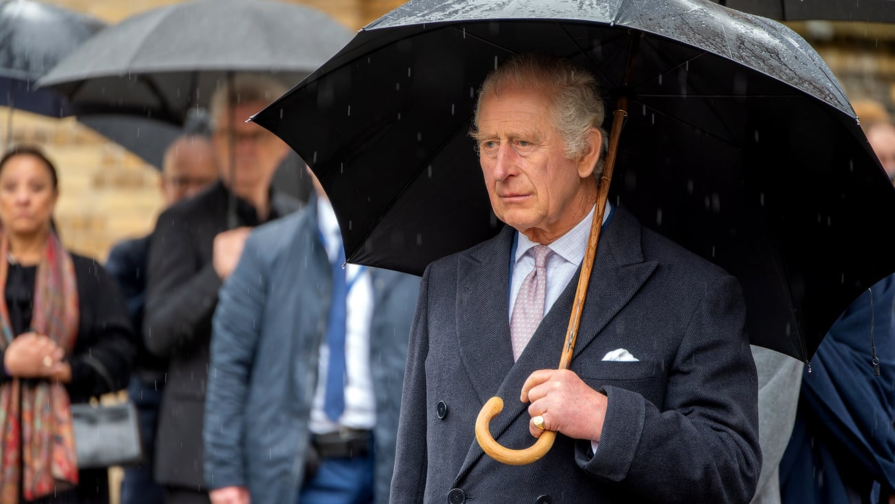 King Charles III in a suit with an umbrella