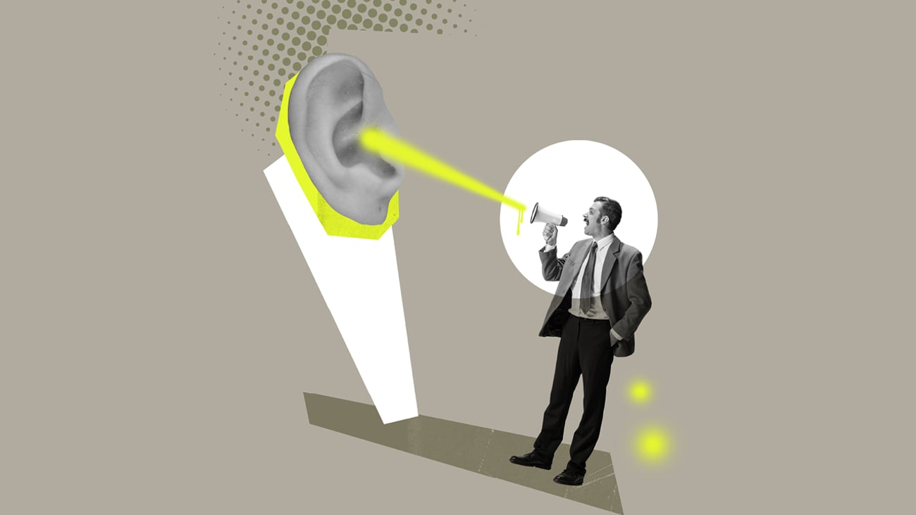 Man in a suit speaking through a megaphone into a giant ear