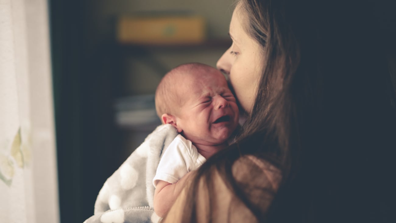 Small infant child crying in woman's arms