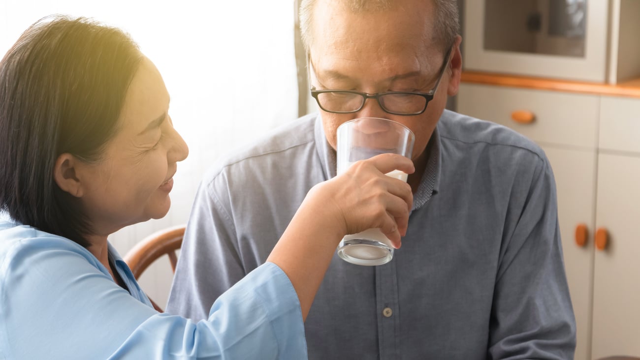 Asian woman giving medicine to older asian man