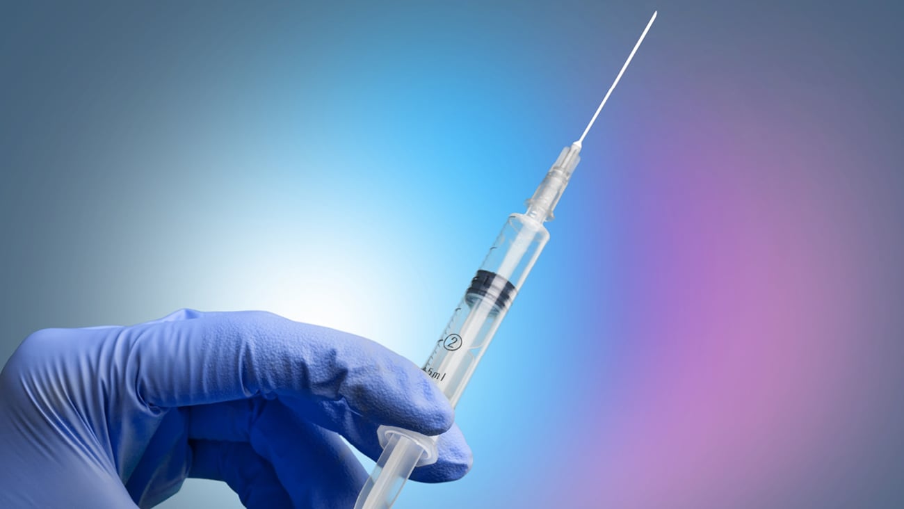 A blue hand holding a vaccine in a syringe