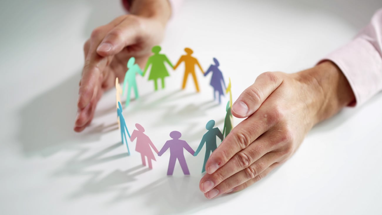 Woman's hands surrounding paper cutouts of people