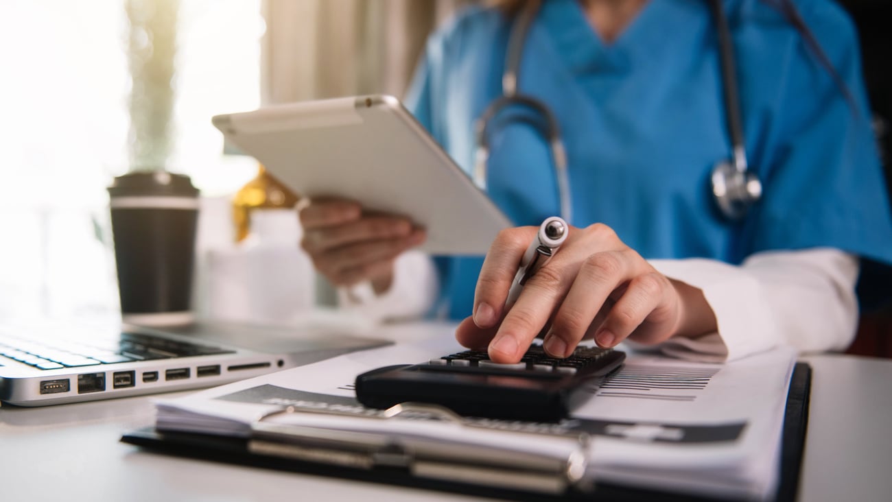 Woman doctor using a calculator to deal with some financial documents