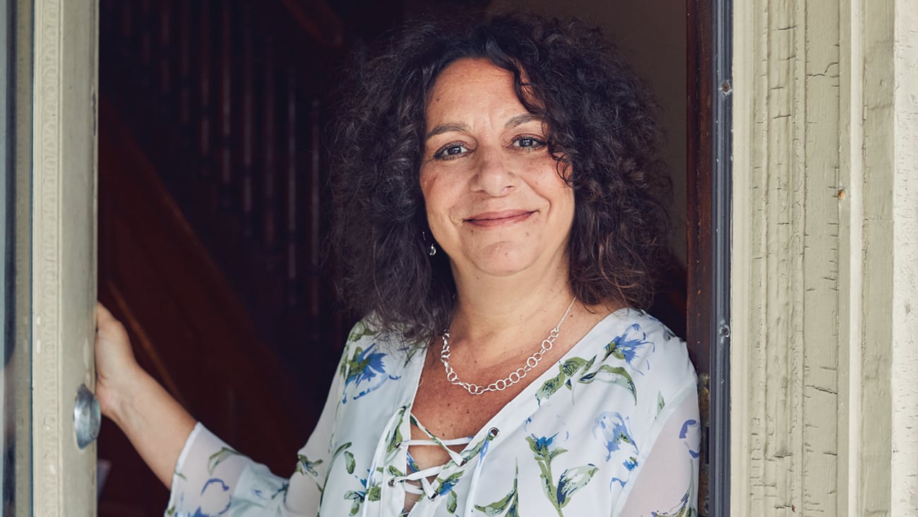 Nanci Frank, consultant pharmacist, smiling in a doorway in a light blue dress