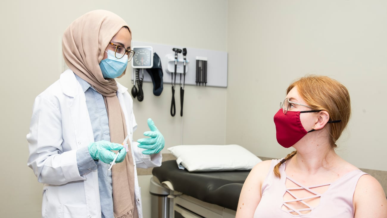 Female pharmacist in headscarf ready to vaccinate female patient