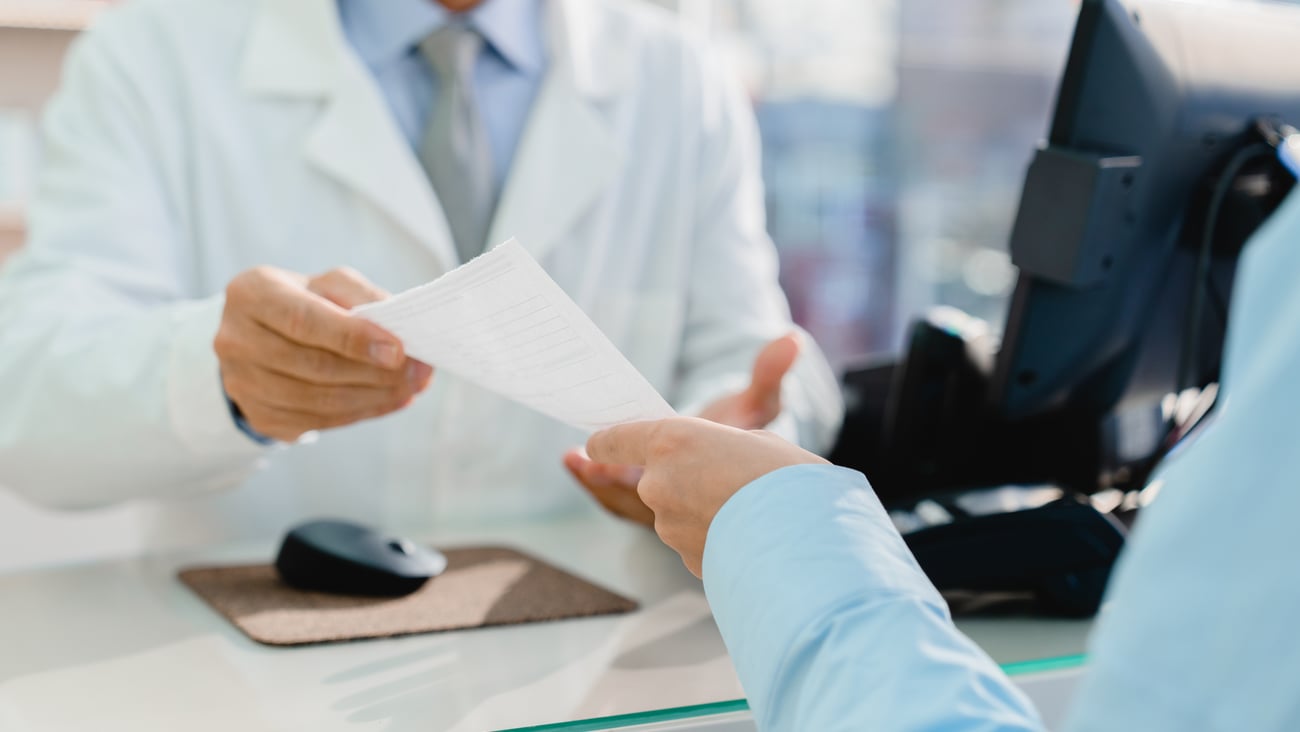 pharmacist handing or getting handed prescription by patient