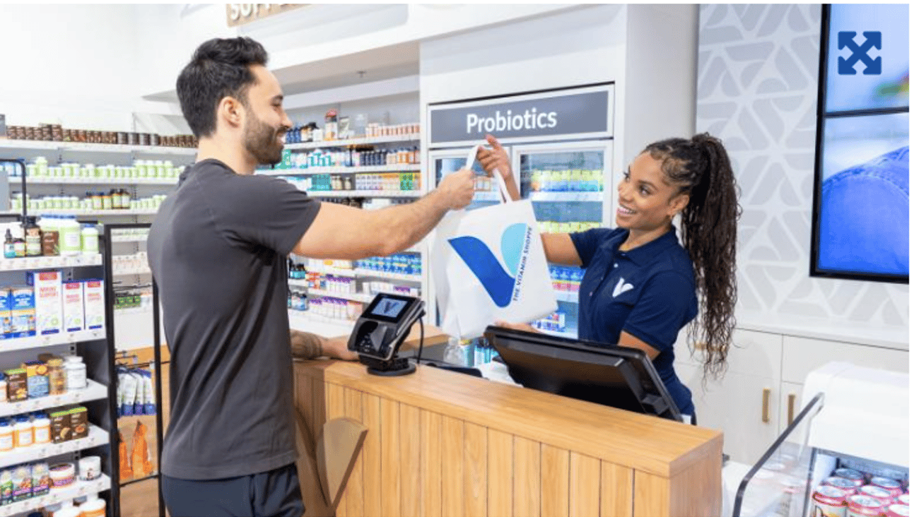 a young white man taking a bag of supplement from a cashier