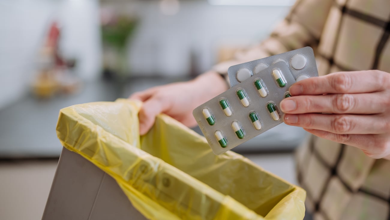 A person is seen throwing out packs of pills in this stock photo. (Shutterstock)