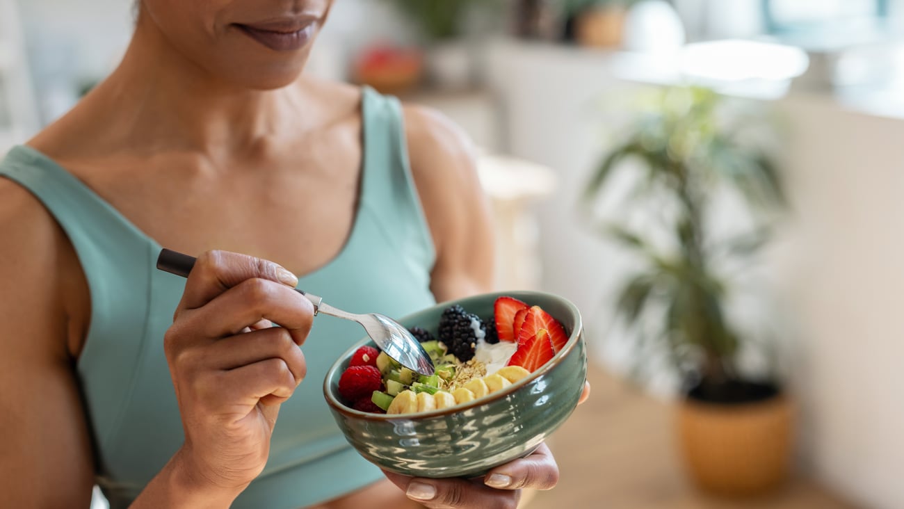 Close up of woman eating a healthy fruit bowl in the kitchen at home