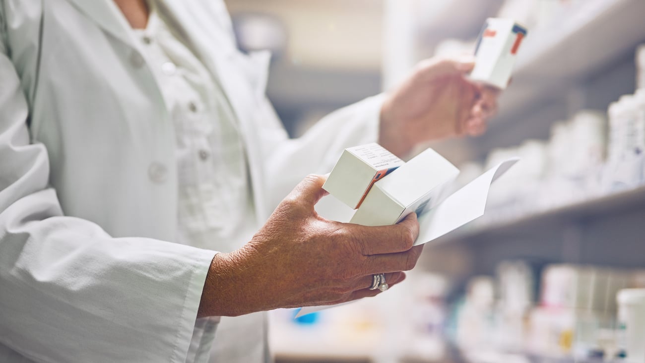 A pharmacists holding boxes of medication.