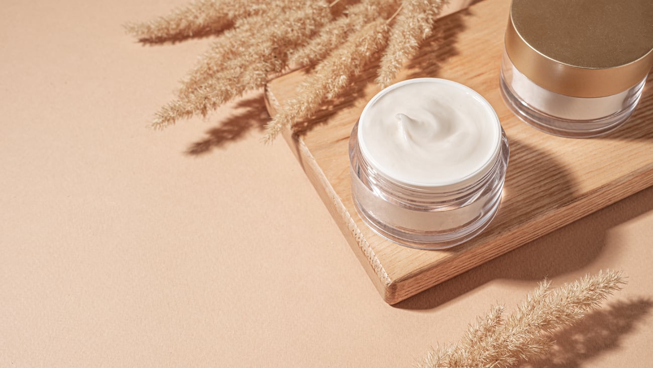 Jars of cosmetic cream with pampas grass on pastel beige background. (Shuttestock)