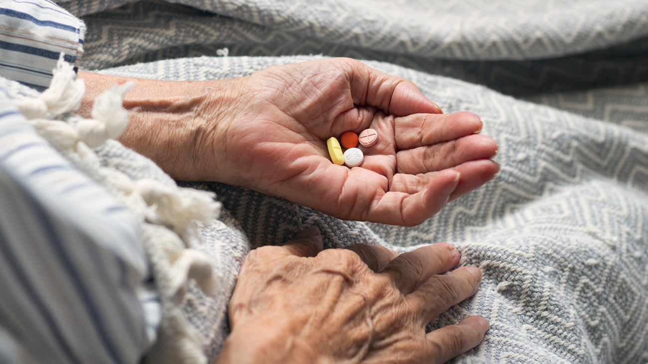 Senior woman's hand holding pills to indicate a potential problem with polypharmacy