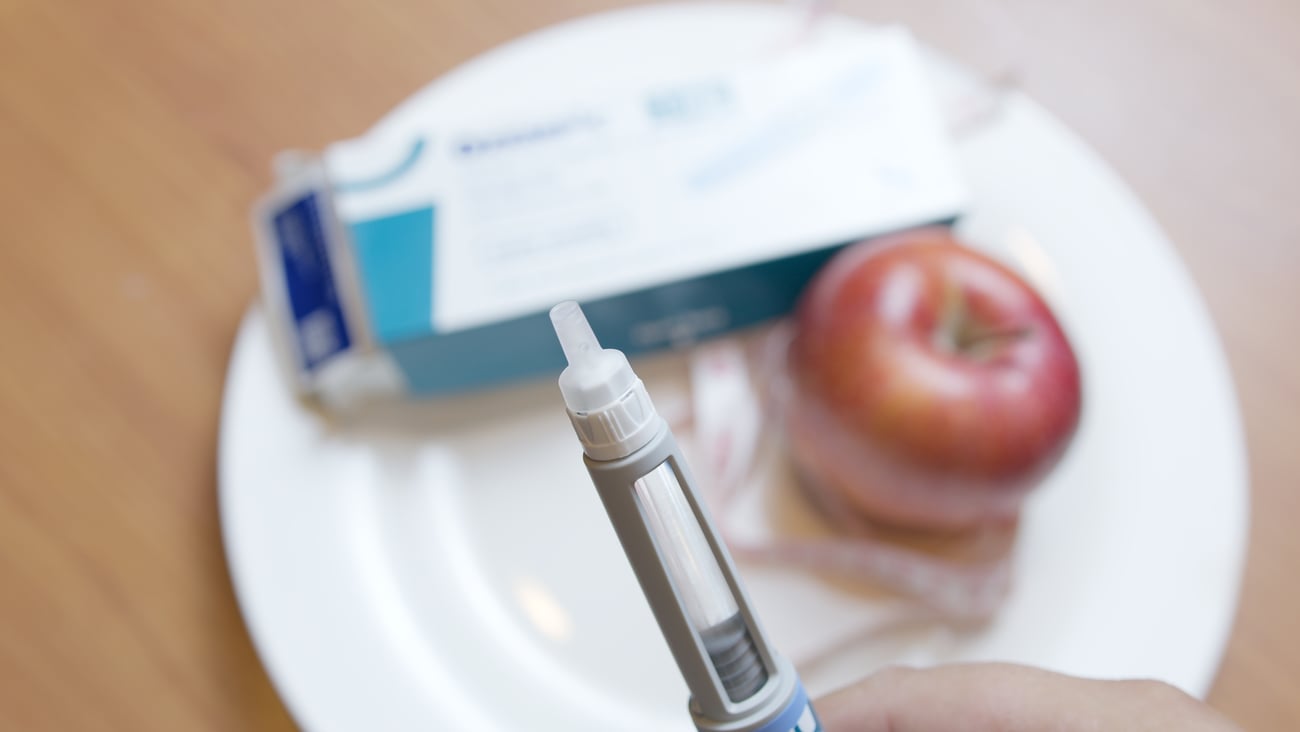 tube of injectable ozempic with apple in the background