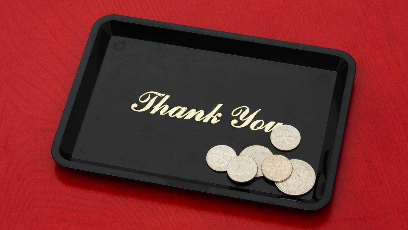 Small black tray that says "thank you" and has coins on it