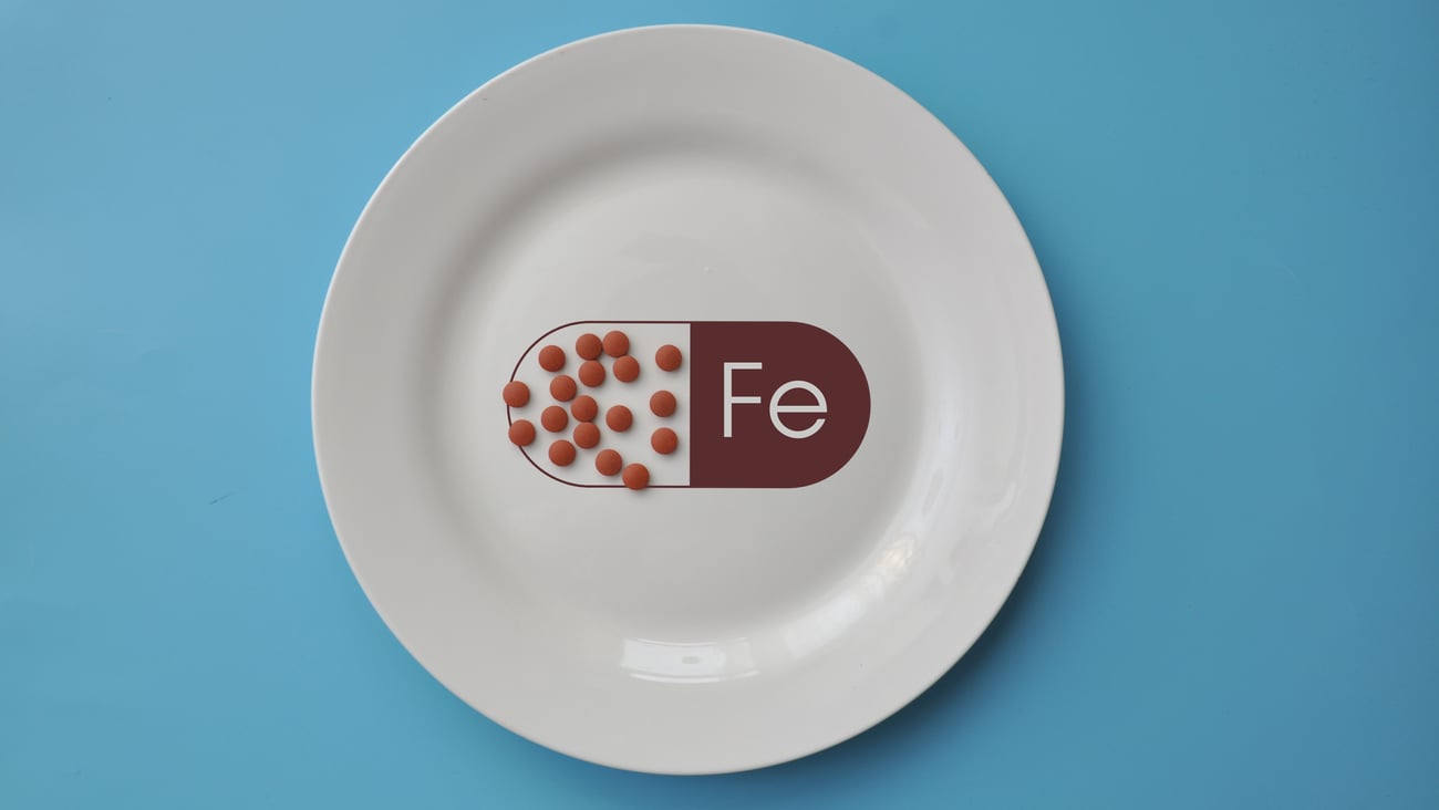 plate with red pills and written symbol for iron, Fe